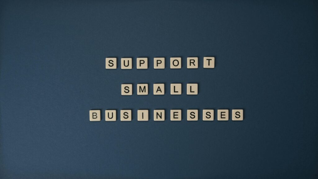 Letter tiles spelling 'Support Small Businesses' on a blue background, promoting local entrepreneurship.